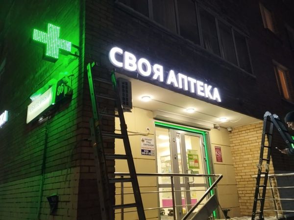 Световая вывеска аптеки на фасаде ночью