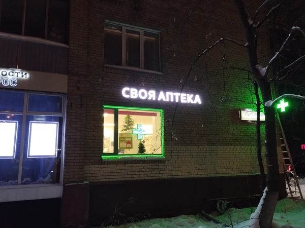 Фасад аптеки со световыми буквами зимним вечером