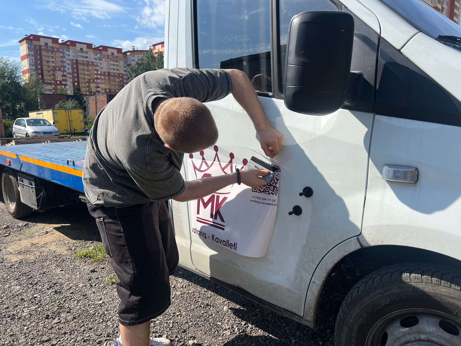 Монтажник прикатывает аппликацию на борт машины